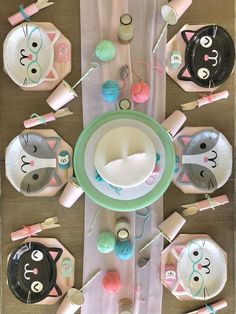 an overhead view of a table set with cats and kittens plates, cups, spoons and crochet hooks