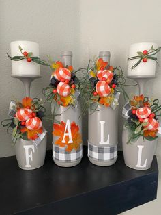 three vases decorated with fall decorations on top of a shelf