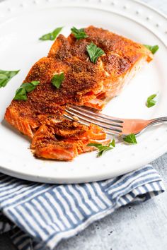 a piece of salmon on a white plate with a fork