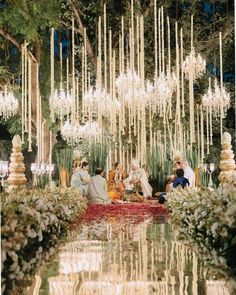 a group of people sitting on top of a lush green field under a chandelier