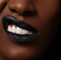 a woman with black lipstick and white teeth