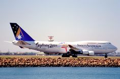 an airplane that is sitting on the tarmac near some water and rocks, with another plane in the background