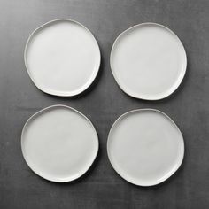 four white plates sitting on top of a black countertop next to an empty plate