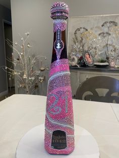 a bottle that has been decorated with pink and silver glitters on the top, sitting on a white table