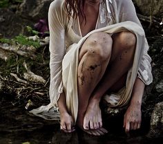 a woman with blood all over her body sitting on the ground