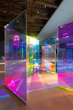 an empty room with brightly colored lights on the walls and floor, as seen through glass partitions