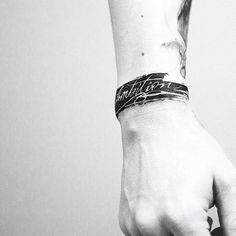 black and white photograph of a person's arm with a tattoo on it