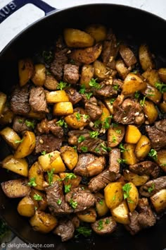 steak and potatoes in a skillet with parsley on top, ready to be eaten