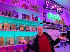 an older man standing in front of a store display filled with books and other items