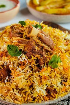 a close up of a plate of food with meat and rice on it, next to other dishes