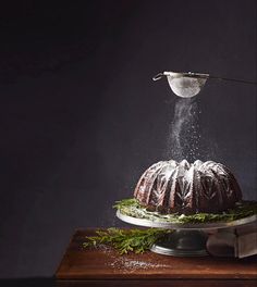 a bundt cake is being sprinkled with icing on a wooden table