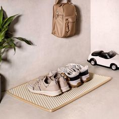 two pairs of shoes are sitting on a mat next to a plant and a purse