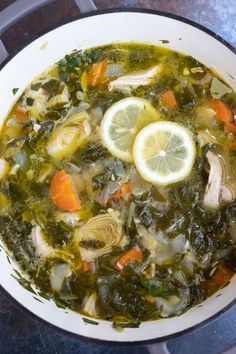 a white bowl filled with soup and lemon wedges on top of a stovetop