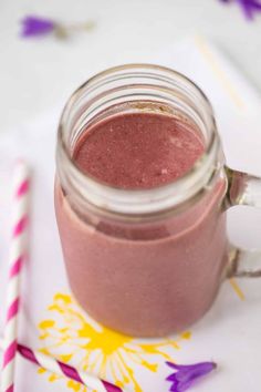 a smoothie in a mason jar next to a straw on a napkin with flowers