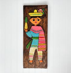 a wooden plaque with a painting of a mexican girl holding a pineapple in her hand