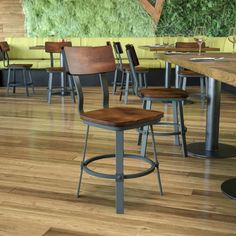 an empty restaurant with tables and stools in front of a moss wall on the wall