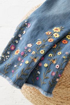 a straw hat with flowers on it and a blue jean jacket hanging from the side