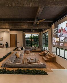 a large living room with couches and televisions on the wall in front of it