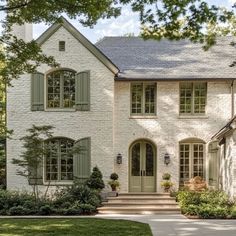 a large white brick house with green shutters