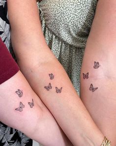 two women with tattoos on their arms holding each other's hands and both have butterflies tattooed on them