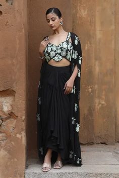 Black floral embroidered cape featuring split sleeves and an open neckline. Paired with a padded sweetheart neck bustier and a draped skirt with button closure., Fit: Relaxed Party Pre-draped Saree With Floral Embroidery, Evening Georgette Pre-draped Saree With Floral Embroidery, Evening Pre-draped Georgette Saree With Floral Embroidery, Evening Cape Sets Made Of Georgette, Party Sets With Draped Floral Embroidery, Party Sets With Floral Embroidery And Draped Shape, Elegant Floral Embroidery Pre-draped Saree, Fitted Floral Embroidery Sets With Cape Sleeves, Georgette Sets With Draped Sleeves