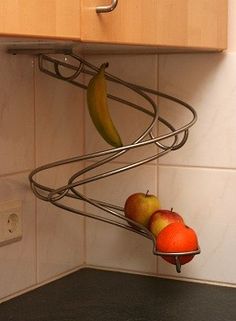 a metal rack holding fruit on top of a kitchen counter