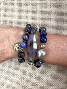 I love when I use one strand get 3 beautiful and coordinating bracelets. These 3 beauties are made of smooth 10 mm tigers eye in purple and brown tones.  Some of the elements consist of a large purple agate focal, Tibetan brass lapis beads, brass rings, wood beads, freshwater pearls, brass bead and brass charm. They are all strung on elastic and are sold as a set. One of a kind. All of my pieces are created with great care, quality elements and attention to detail. I hope you are happy with your purchase and should you have any concerns or questions, please let me know. I am happy to help. Every item is handmade so please use care when wearing and storing. Please avoid wearing in the water and using oils, lotion and any chemicals so the quality of the stones and metals can be best protecte Handmade Market, Purple Agate, Hippie Bracelets, Beads Bracelet Design, Brass Charms, Wood Beads, Bracelet Designs, Bracelet Set, Freshwater Pearls