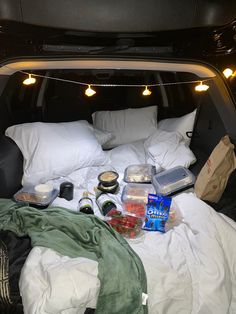 the back of a van with food and drinks in it's trunk, under lights