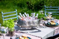 an outdoor table set with silverware and wine glasses