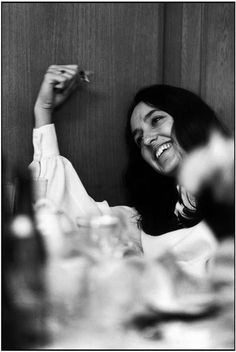 a woman sitting at a table with food in front of her smiling and raising her arm