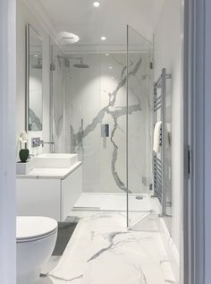 a white bathroom with marble flooring and glass shower door, along with a toilet and sink