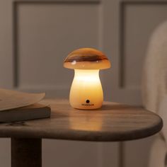 a mushroom lamp sitting on top of a wooden table next to a book and chair