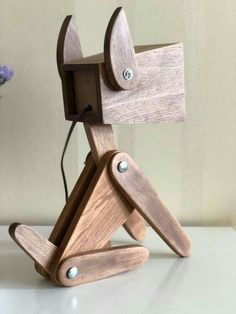 a wooden lamp that is on top of a white table with flowers in the background