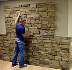 a man is working on a wall made out of stacked stone blocks in an office