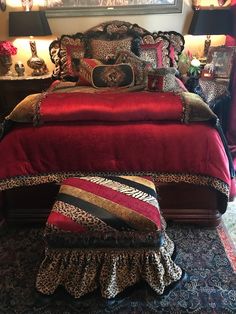 a red bed with leopard print pillows and matching foot stools in front of it