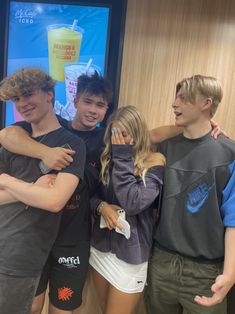 four young people standing together in front of a poster