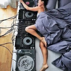 a woman laying on top of a bed next to a dj's turntable