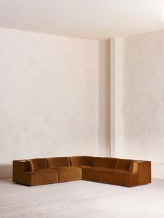 a corner couch in an empty room with white walls