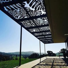 the sun shines on an outdoor patio with metal structure and trees in the background