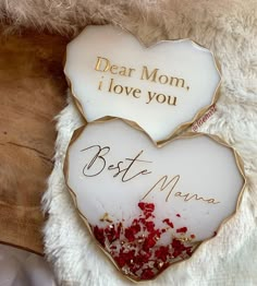 two heart - shaped plaques with writing on them sitting on a white fur covered surface