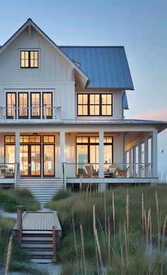 a large white house sitting on top of a lush green field next to tall grass