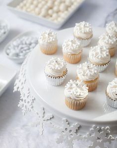 cupcakes are arranged on a white cake plate with an angel figurine next to them