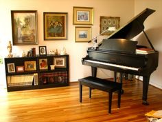 there is a piano in the living room with pictures on the wall and a bench next to it