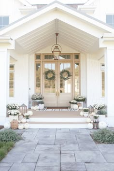 a white house with two front doors and wreaths