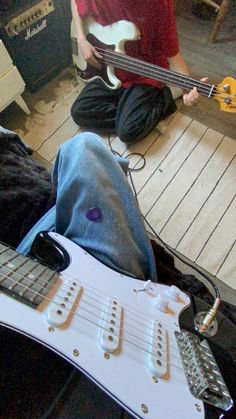 a man sitting on the floor playing an electric guitar