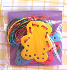 several different colored pieces of plastic string on a checkered tablecloth with a purple bag in the foreground