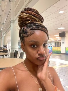 a woman with braids on her head sitting at a table in an office building