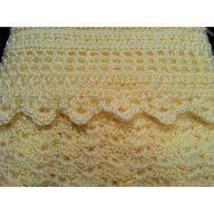 a yellow crocheted blanket with scalloped edges