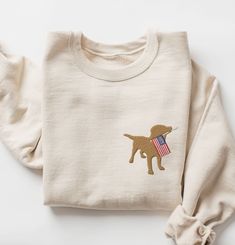 These unisex cozy sweatshirts (we use Gildan) are embroidered with a yellow lab holding a USA flag 😀 *Please note, the thread we use is golden yellow in color Please reach out if you would like a color you don't see listed! We have many more but we can only list a certain amount on Etsy. * 50% cotton, 50% polyester * Pre-shrunk * Classic fit * 1x1 athletic rib knit collar with spandex * Air-jet spun yarn with a soft feel and reduced pilling * Double-needle stitched collar, shoulders, armholes, cuffs, and hem SIZING: Please ensure you check measurement chart before ordering as shirts are printed once you place your order. Sweatshirts are unisex sizes but they fit true to size for ladies. Please size up if you want a roomier fit. If you have any questions about sizing, please feel free to a Usa Flag Sweater, Flag Sweater, Chocolate Labrador Retriever, American Flag Sweater, Usa Sweatshirt, Chocolate Labrador, Yellow Lab, Chocolate Lab, American Flag Shirt