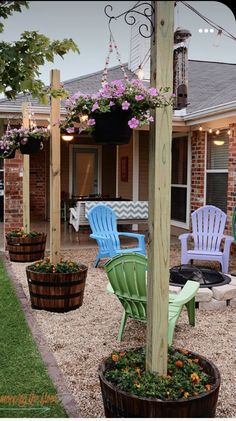 some chairs are sitting on the gravel in front of a house with flowers and lights